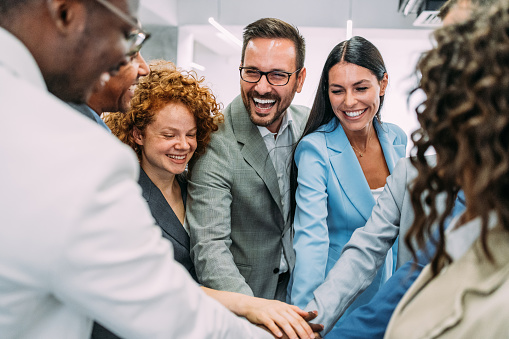 Shot of multiracial group of business people with stacked hands showing unity and teamwork. Successful business people stacking hands in the office.