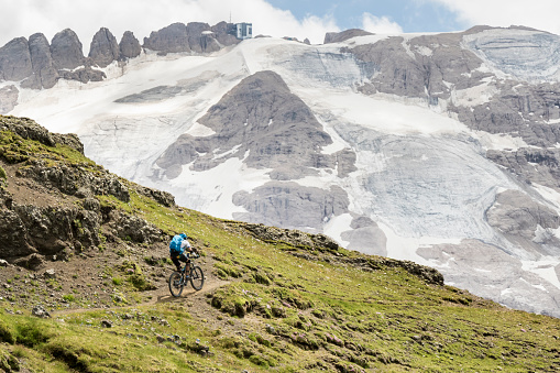 A lonely male mountainbiker ist riding on a narrow footpath towards the partly glacier covered north side of Mt. Marmolada (3.343 mt., 10.968 ft.), the highest mountain of the Dolomites, Italy.\nCanon EOS 760D, 1/1000, f/8, 95 mm.