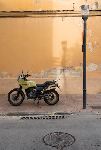 Barcelona, Spain - October 23, 2022: A Royal Enfield Himalayan motorcycle with a knobby wheel and mud, parked on the curb