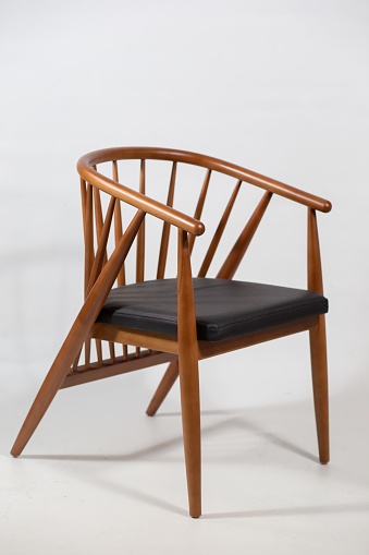 A vertical shot of a wooden chair behind a white background