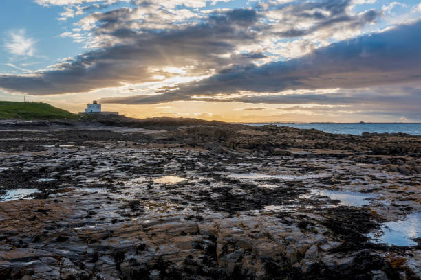 le phare de bamburgh depuis le coucher de soleil de harkness rocks - northumberland england bamburgh lighthouse beach photos et images de collection