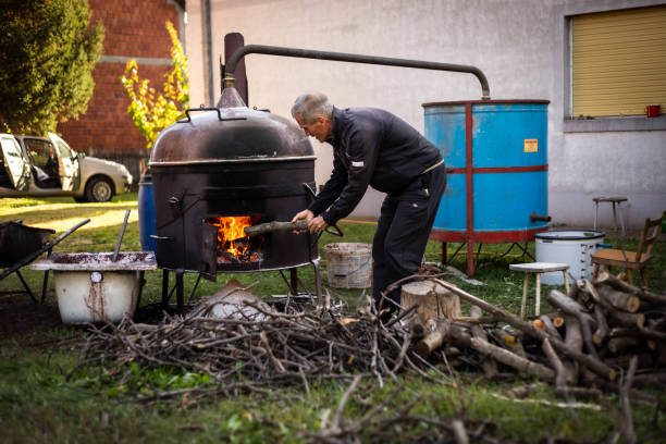 der mann setzt wälder in brand und macht hausgemachtes alkoholisches getränk raki "brandy". - destillationsturm stock-fotos und bilder