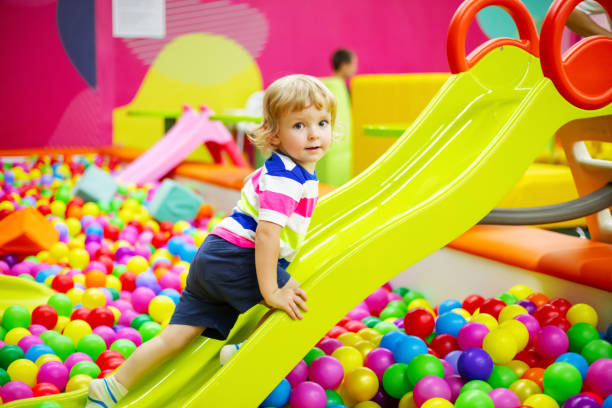 istock Little boy riding on slide at indoor play center 1439245394