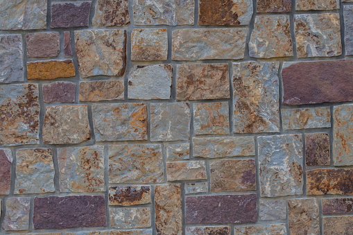 Old stone wall for backgrounds of red, tan, orange and brown in rural Montana in northwest USA, North America.