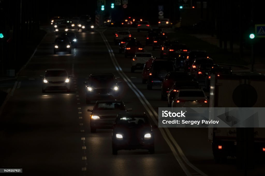 cars driving on the evening road cars with headlights on driving on a city road in the evening Air Pollution Stock Photo