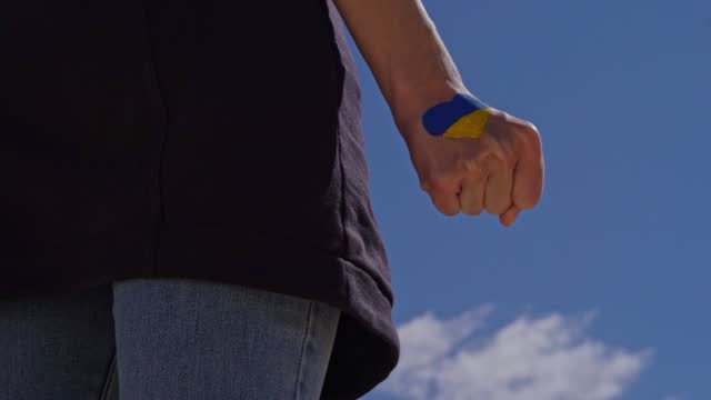 female fist painted in Ukraine flag colors with heart shape