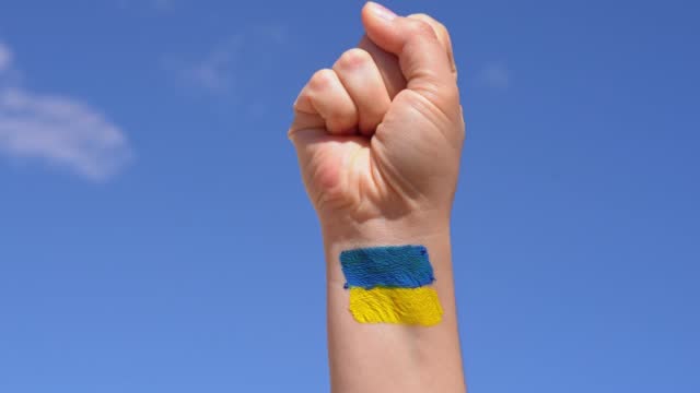 female fist painted in Ukraine flag colors