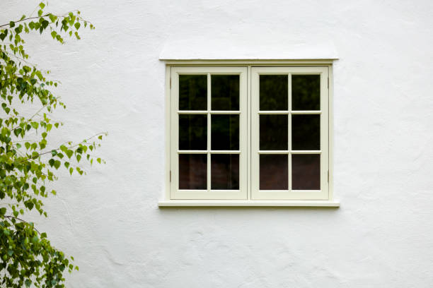 House exterior with wooden window and white wall rendering, UK