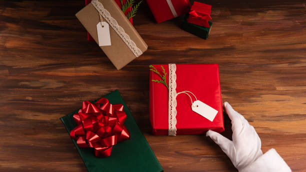 Santa giving a red gift box over a wood floor, white label for mock up stock photo