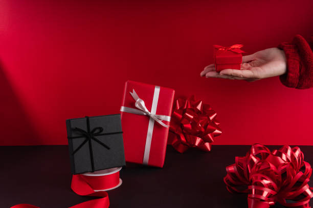 Hand of a Woman Holding a wrapped red small christmas present stock photo