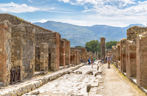 Pompeii - May 13, 2014: Pompeii street view, Naples, Italy. Panorama of Ancient Roman houses ruins, road, sky and mountain. Theme of travel in Pompeii city, tourism, sightseeing and civilization.