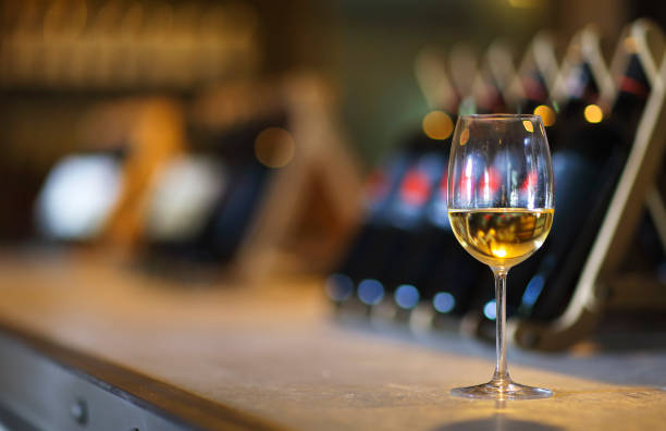 Wine bottles on a wooden shelf. Wine bar. Wine bottles on a wooden shelf. Wine bar. Close up on glass of white wine wine bar counter stock pictures, royalty-free photos & images