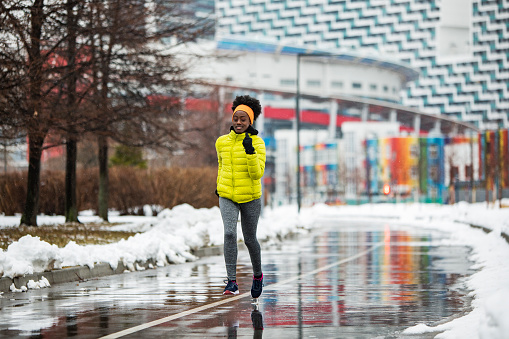 Young African woman training outdoors in bad weather