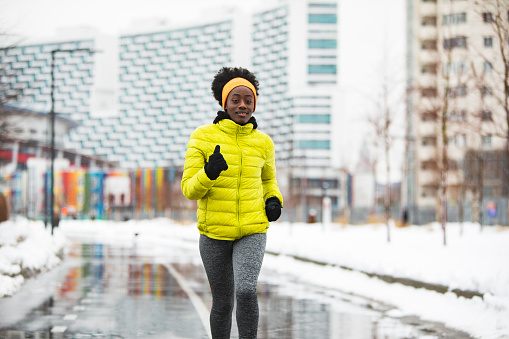 Young African woman training outdoors in bad weather