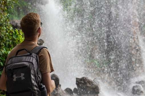 Nice, France – October 27, 2019: Young white male looks at a waterfall in Nice, France during a hike in nature