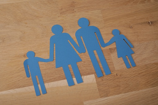 A closeup shot of blue female and male icons of a family on a wooden background