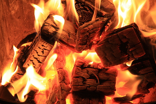 a burning fireplace stove with wood and pellets in the foreground
