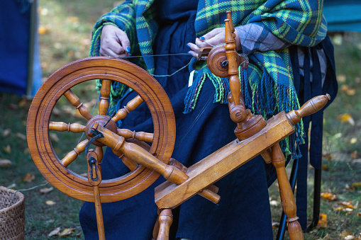 Woman spinning yarn on an old spinning wheel