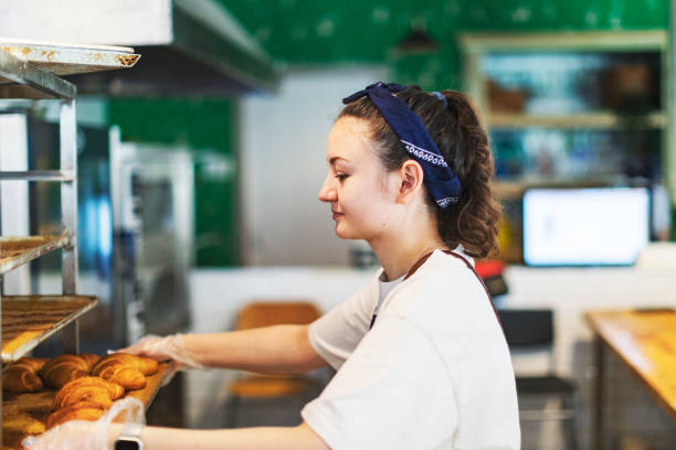 istock Young woman taking cooling rack with Fresh croissants 1439276945