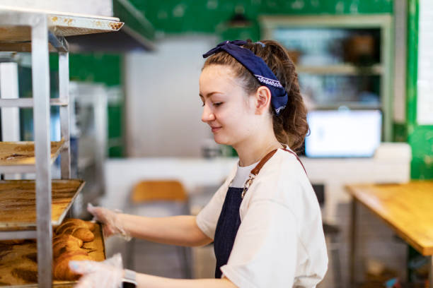 istock Young woman taking cooling rack with Fresh croissants 1439277057