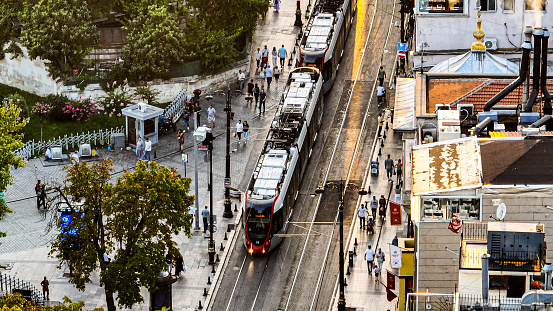 Aerial view of Public Transport Tram Train passing over Sultanahmet station in Sunset Istanbul. \n\nSultanahmet Tram Station is a level tram station located on the T1 (Bağcılar - Kabataş) Tram Line of the Istanbul tram and put into service on 10 July 1992.\n\nThe station is located on Divanyolu Street, at the northern end of Sultanahmet Square, between Alemdar District and Binbirdirek District in Fatih district.