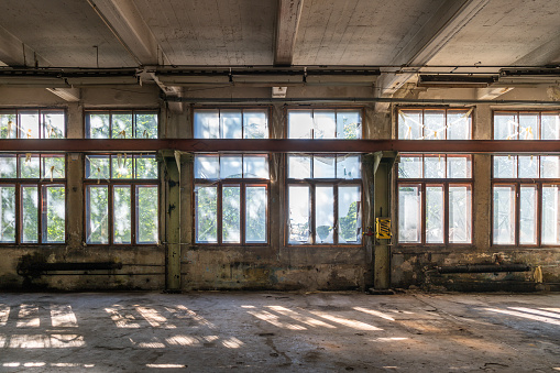 Abandoned multi-story brick factory building with broken glass windows.