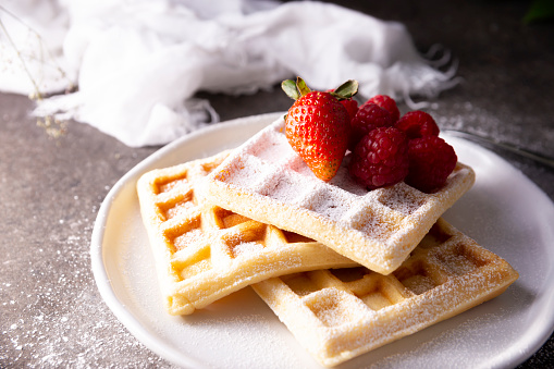 Breakfast plate of waffles and raspberries, butter and maple syrup