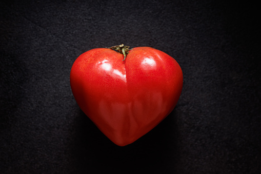 Heart-shaped tomato on a black background. Valentine's tomato
