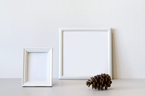 Mock up minimalist home interior with rectangular and square white wooden photo frames and big pine cone. Photo with copy space