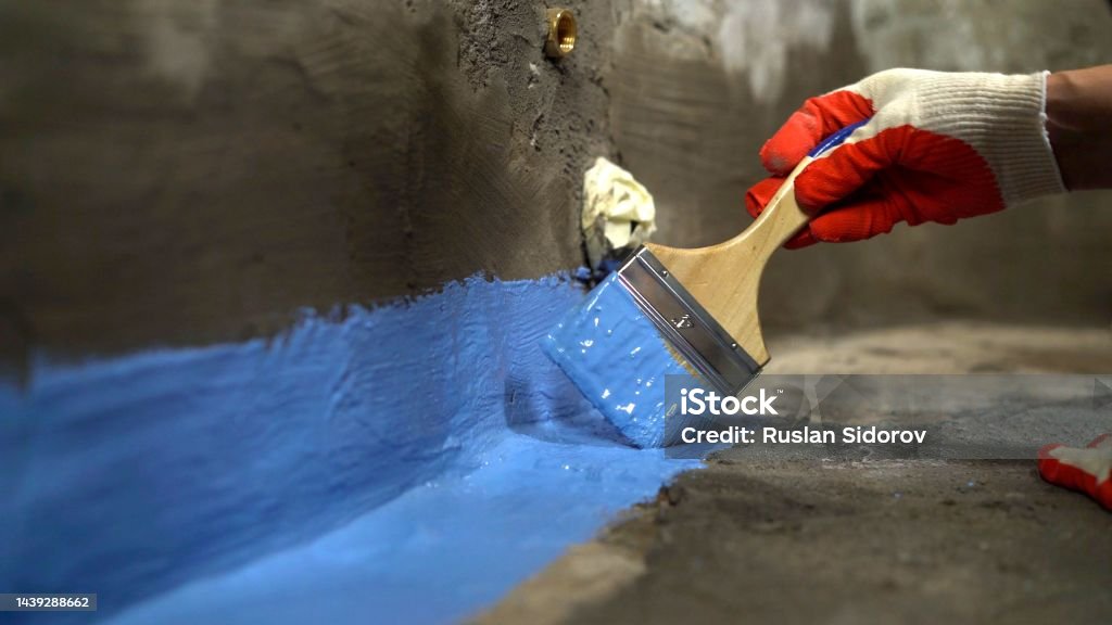Waterproofing the floor with a brush.Waterproofing concrete mortar. The master puts waterproofing on a concrete floor with a brush. Bathroom floor waterproofing. Bathroom floor waterproofing. Waterproofing the floor with a brush.Waterproofing concrete mortar. The master puts waterproofing on a concrete floor with a brush. Waterproof Stock Photo