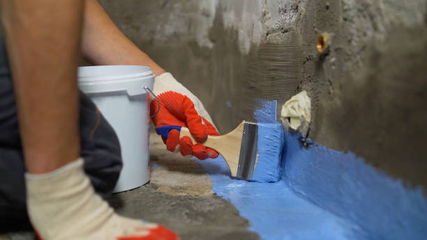 Waterproofing the floor with a brush.Waterproofing concrete mortar. The master puts waterproofing on a concrete floor with a brush. Bathroom floor waterproofing. stock photo