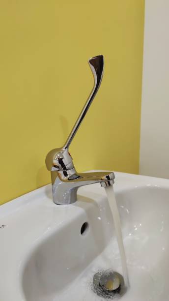 istock faucet with running water, on a yellow background 1439289575