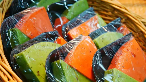 Many packaged platters with red and green cheeses in a wickerbasket close-up