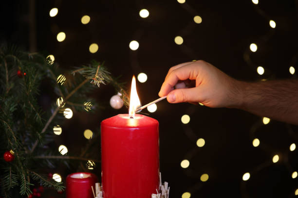 istock Persons hand with match lights red christmas candle 1439294911