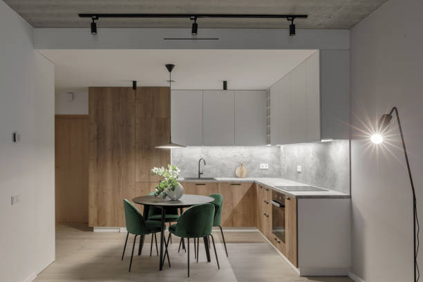 istock Modern minimalistic kitchen and dining room interior with wooden and white surfaces, green chairs and eucalyptus in ceramic vase. Aesthetic simple interior design concept. 1439298374