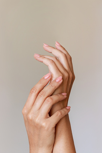 Primer plano de la mano de una mujer con una delicada manicura neutra natural perfecta sobre un fondo beige photo
