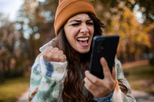 istock Young woman using smartphone in public park 1439302186