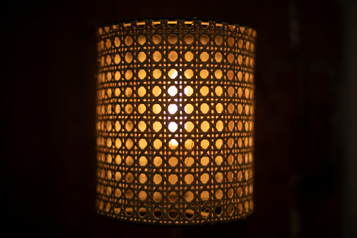 Lamp in dark. Wooden lampshade around incandescent lamp. Minion glows.