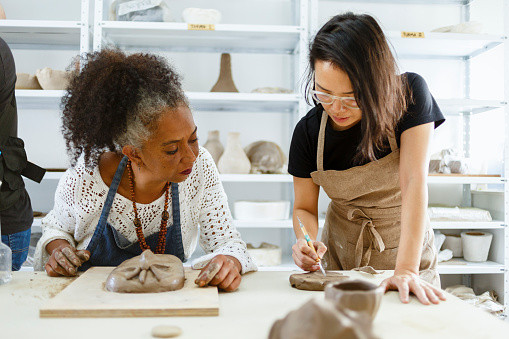 teacher teaching pottery to black woman