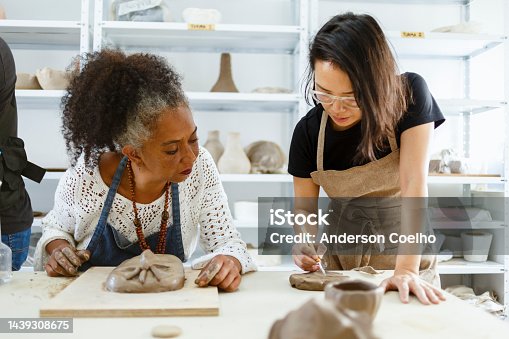 istock teacher teaching pottery to black woman 1439308675