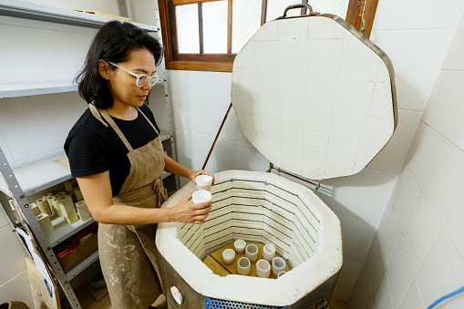 Ceramist drying clay pieces in an oven