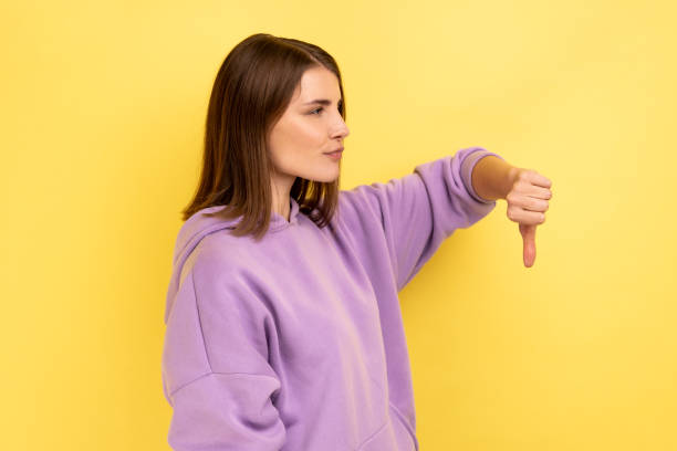 istock Side view of upset dissatisfied woman standing with thumb down, negative feedback. 1439311240