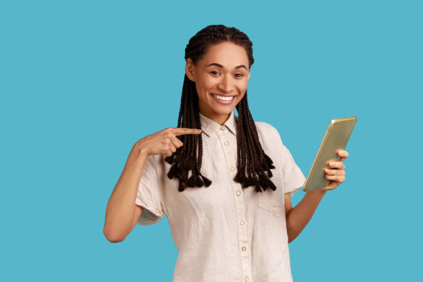 istock Woman using tablet for working online, looking smiling at camera, pointing at display. 1439312450