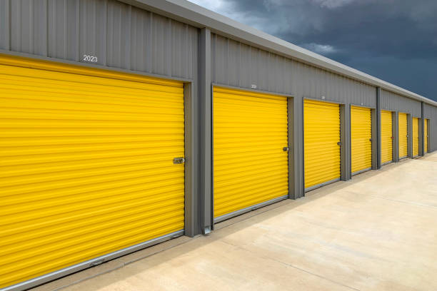 istock Exterior of a commercial warehouse with yellow roller doors, garages, self storage facilities. 1439312499
