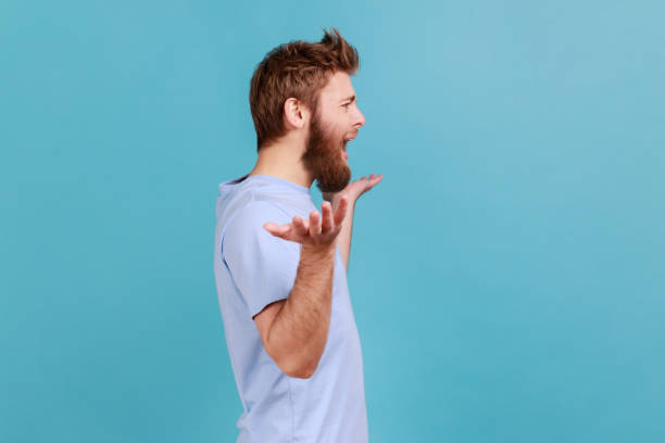 istock Man in blue T-shirt standing with raised hands and indignant face asking why, annoyed by problem. 1439313228