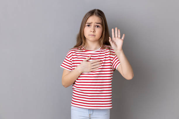 little girl holding hand on heart, swearing to speak truth, honor and conscience. - proof of love imagens e fotografias de stock