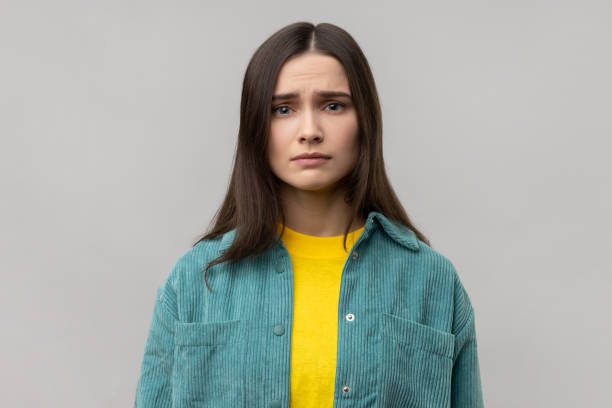 Disappointed woman being upset of bad news, looking at camera with frowning face, expressing sadness Portrait of disappointed woman being upset of bad news, looking at camera with frowning face, expressing sadness, wearing casual style jacket. Indoor studio shot isolated on gray background. Phobia stock pictures, royalty-free photos & images