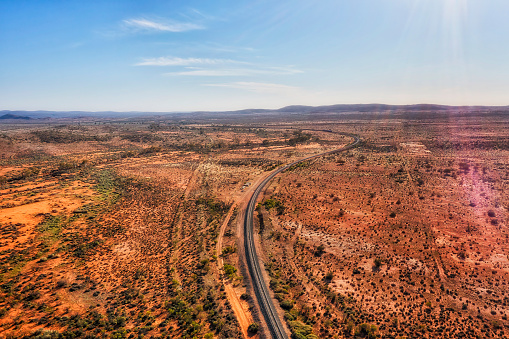 Single railway track railroad in red soil outback to Broken Hill of Far West NSW in Australia - aerial landscape.