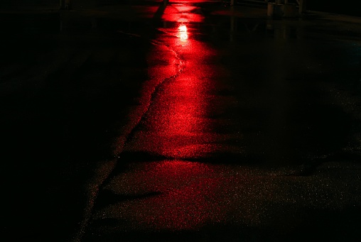 Reflection of a red traffic light on the pavement