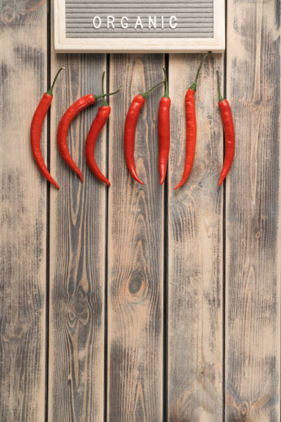 Horizontal line of red hot peppers on faded wooden table, top view. Spicy chillies arranged in order. Organic food or healthy diet concept. Location of objects. Planking. Place for text. línea horizontal de pimientos rojos picantes sobre mesa de madera descolorida, vista superior. chiles picantes dispuestos en orden. concepto de alimentación ecológica o dieta saludable. ubicación de objetos. tablazón. lugar para el texto